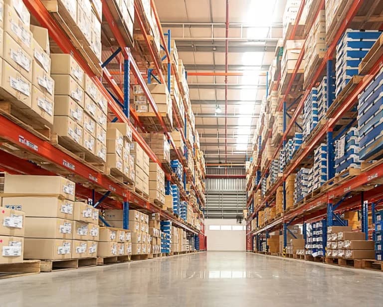Warehouse aisle stacked with pallets, served by Undergrads logistics staff
