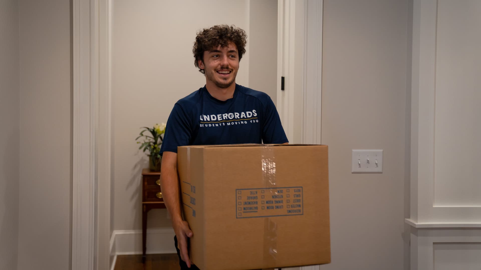 Undergrads mover carrying a box, ready to help on short notice