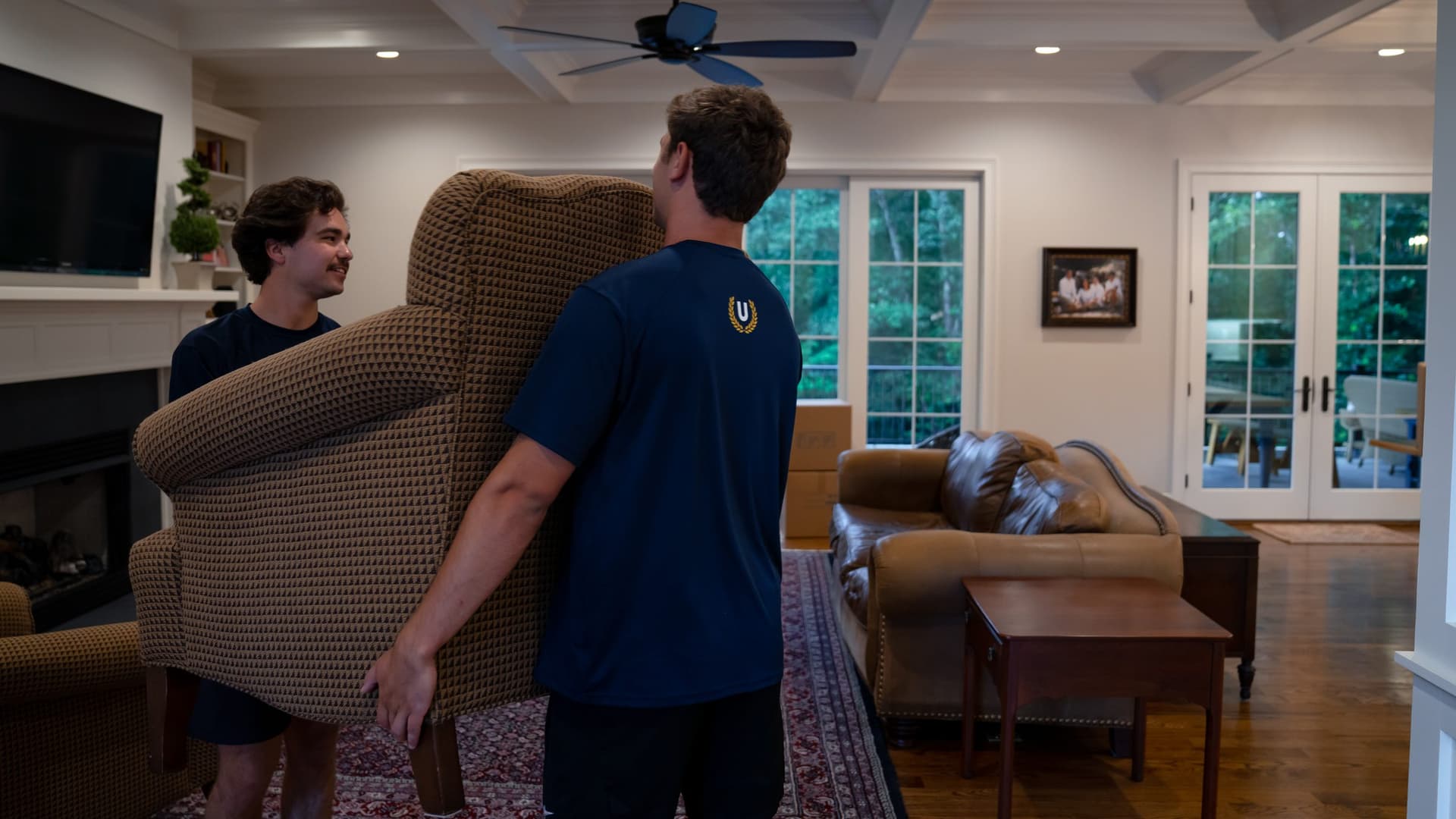 Undergrads crew carrying furniture through an apartment hallway