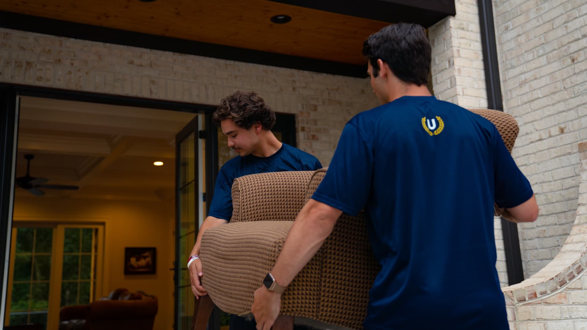 Two Undergrads crew members carefully moving furniture in a home