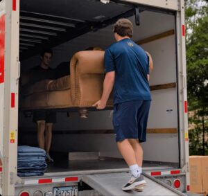Two Undergrads Moving Movers Unloading a Sofa from a Truck